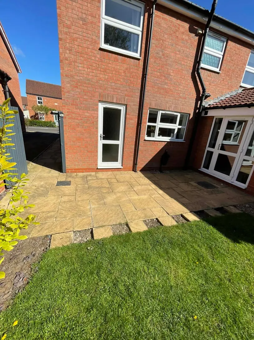 Buff paving patio with lawn at the rear of a house