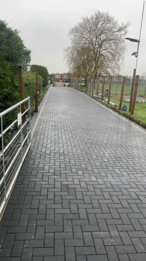 Long charcoal block paved path beside railings